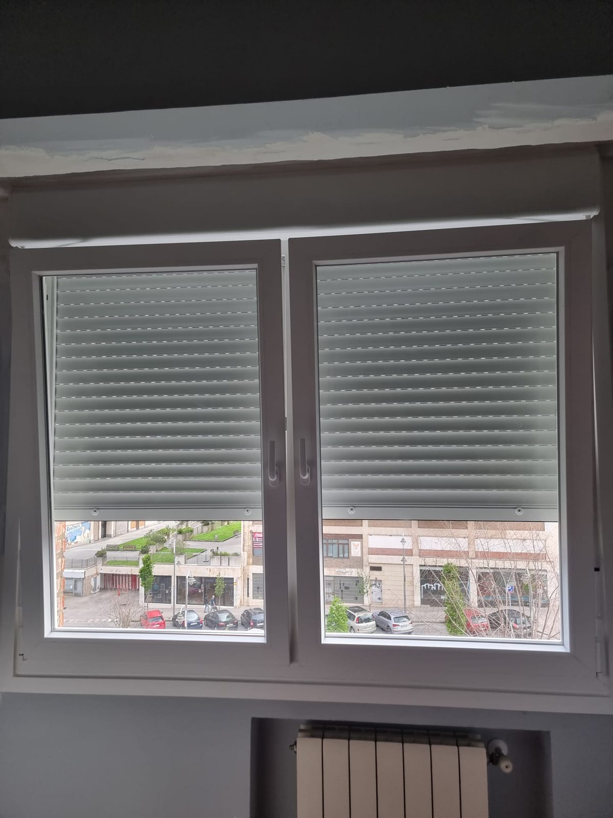 Ventana de dos hojas con persianas de aluminio gris a media altura