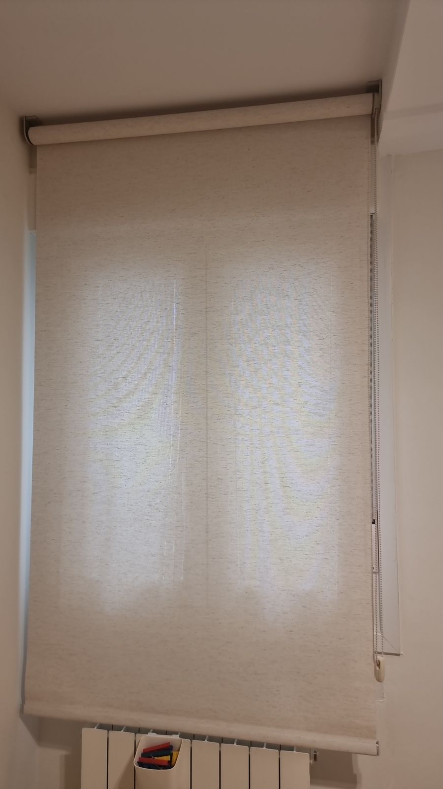 Estor enrollable beige traslúcido bajado en una ventana