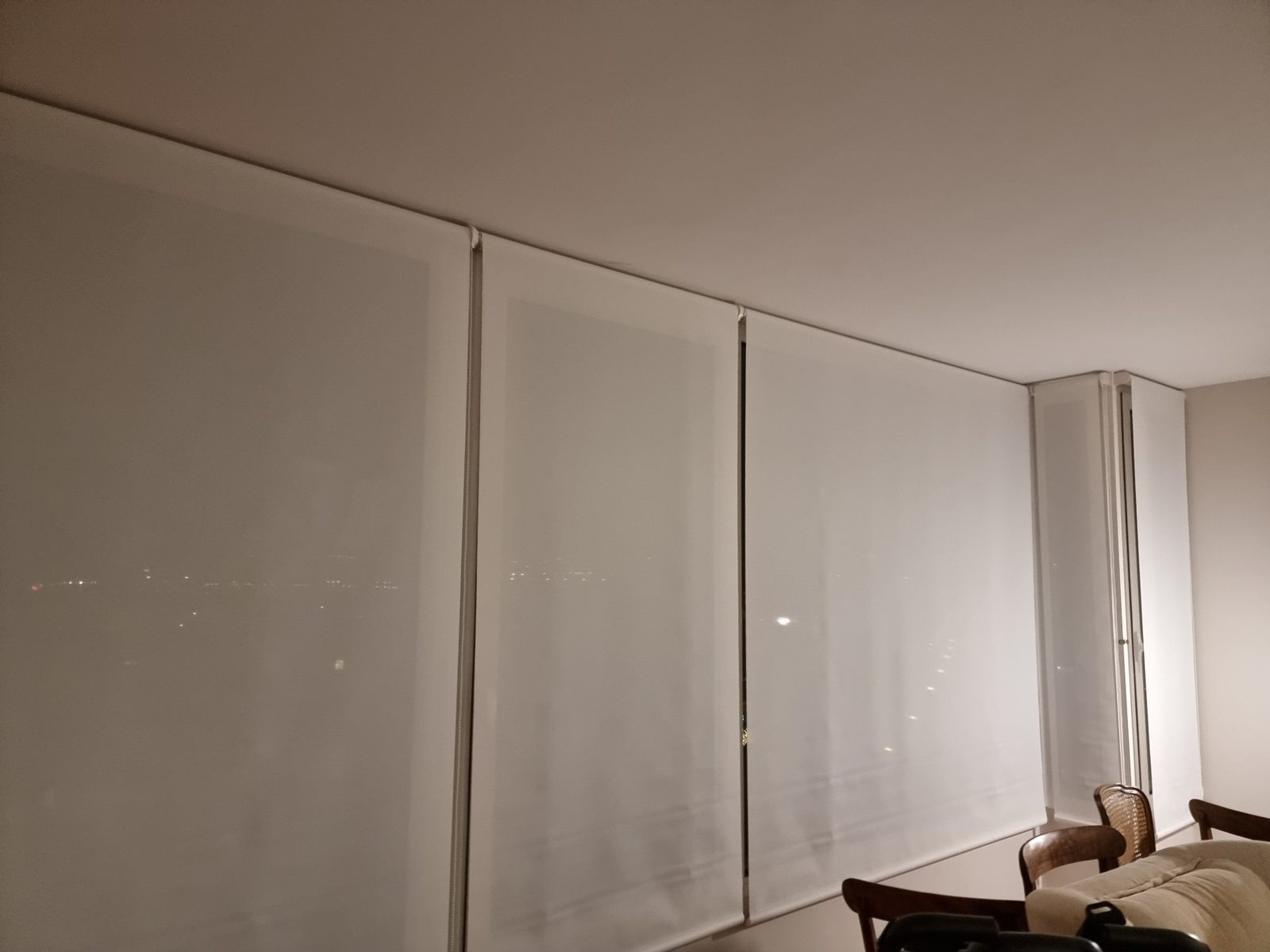 Salón con tres estores enrollables blancos cubriendo una pared de ventanas
